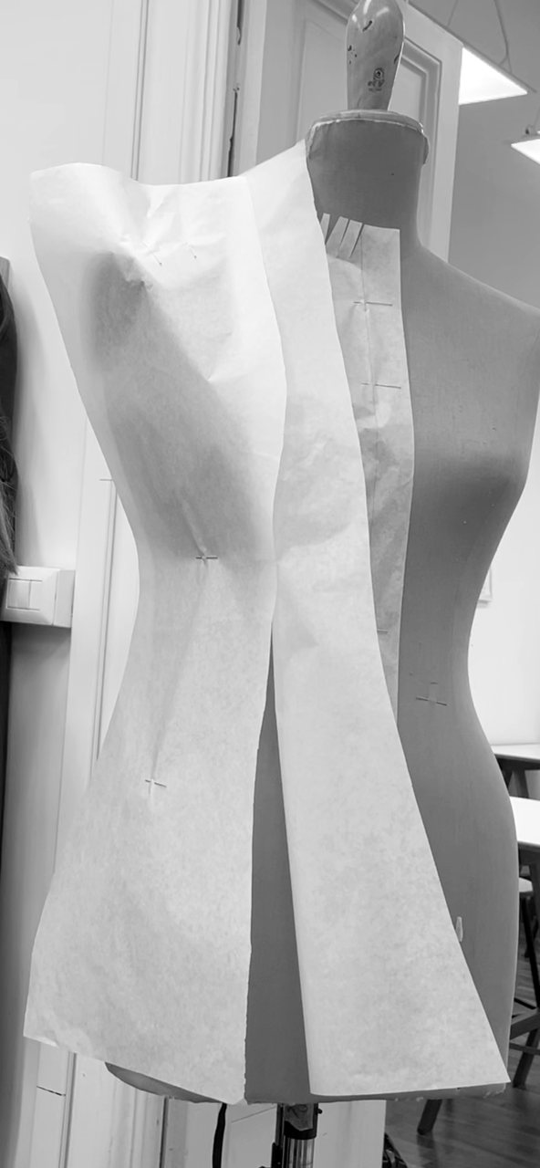Pattern paper draped and pinned on the dress form, princess seams shaped and balance points marked